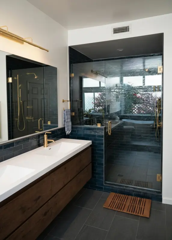 Deep blue tiled bathroom with brass fixtures and a walk-in glass shower