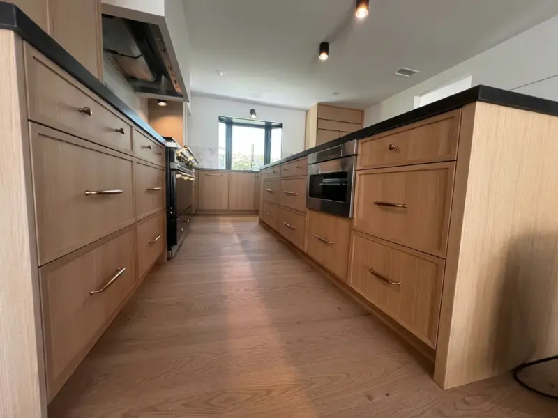 White oak cabinetry with a marble backsplash and black range