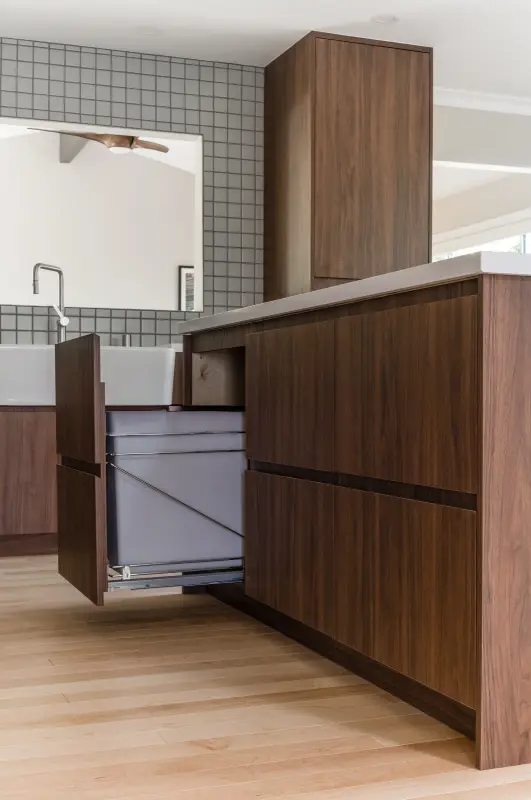 Handleless walnut island with a concealed trash pull-out